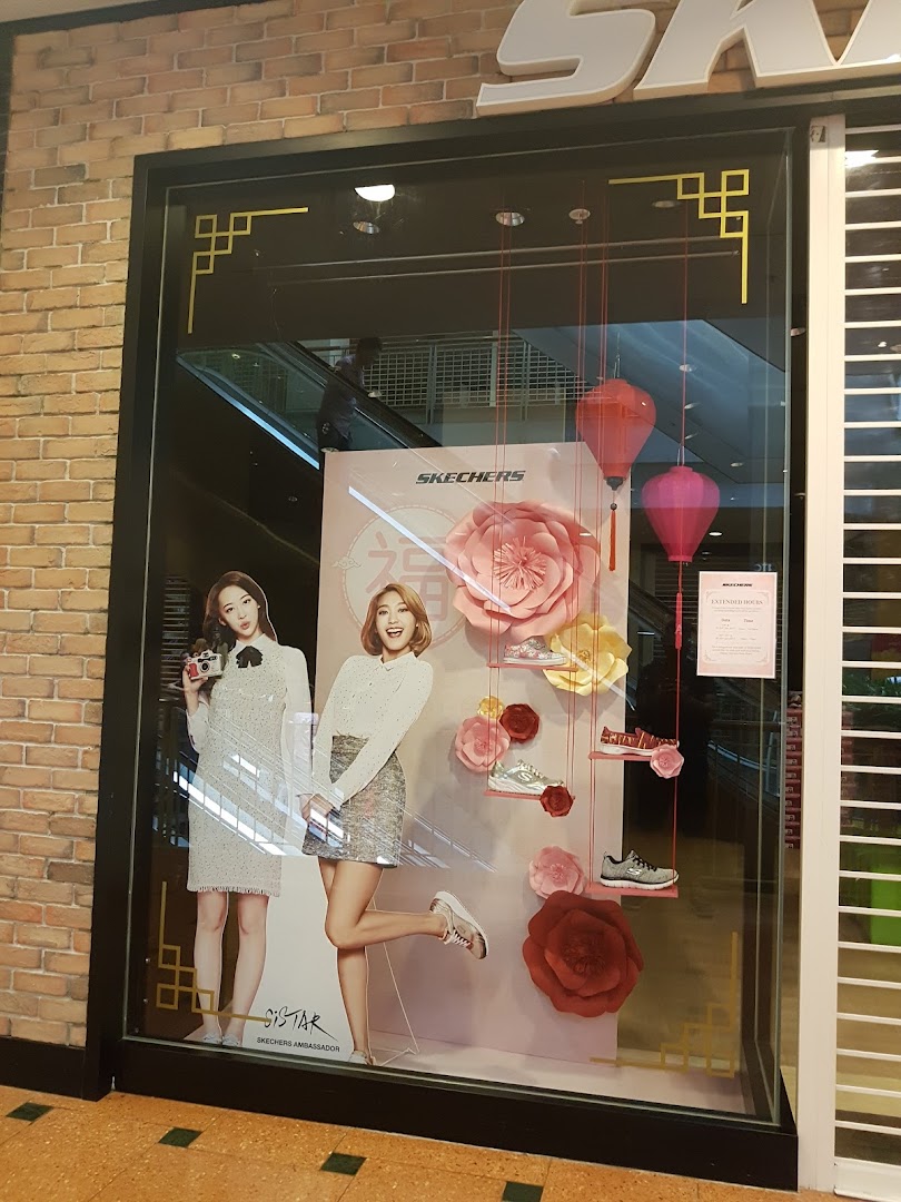 A vibrant Skechers shop window display featuring models, various shoe styles, and large floral decorations.