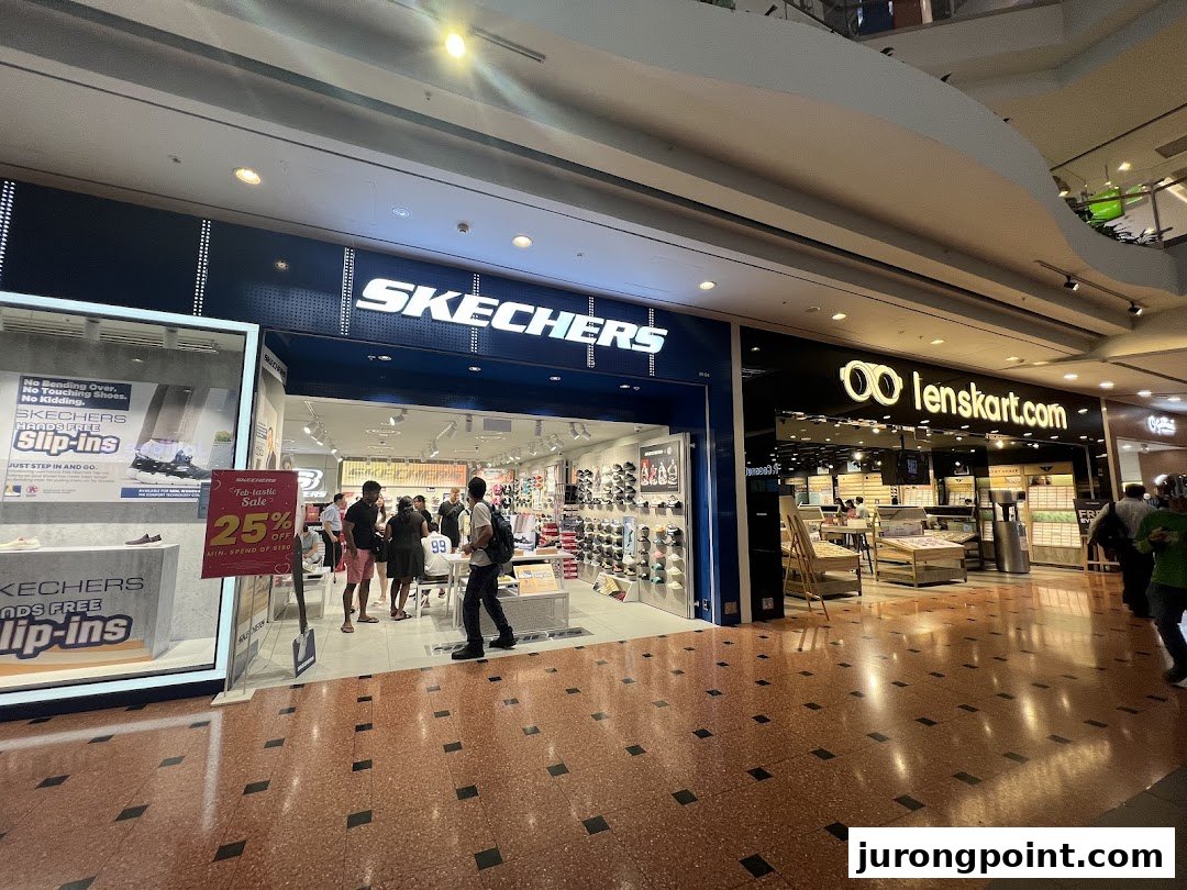 The Skechers shop entrance is bustling with customers, featuring a prominent 'Hands Free Slip-ins' display and a 'Feb-tastic Sale' sign.