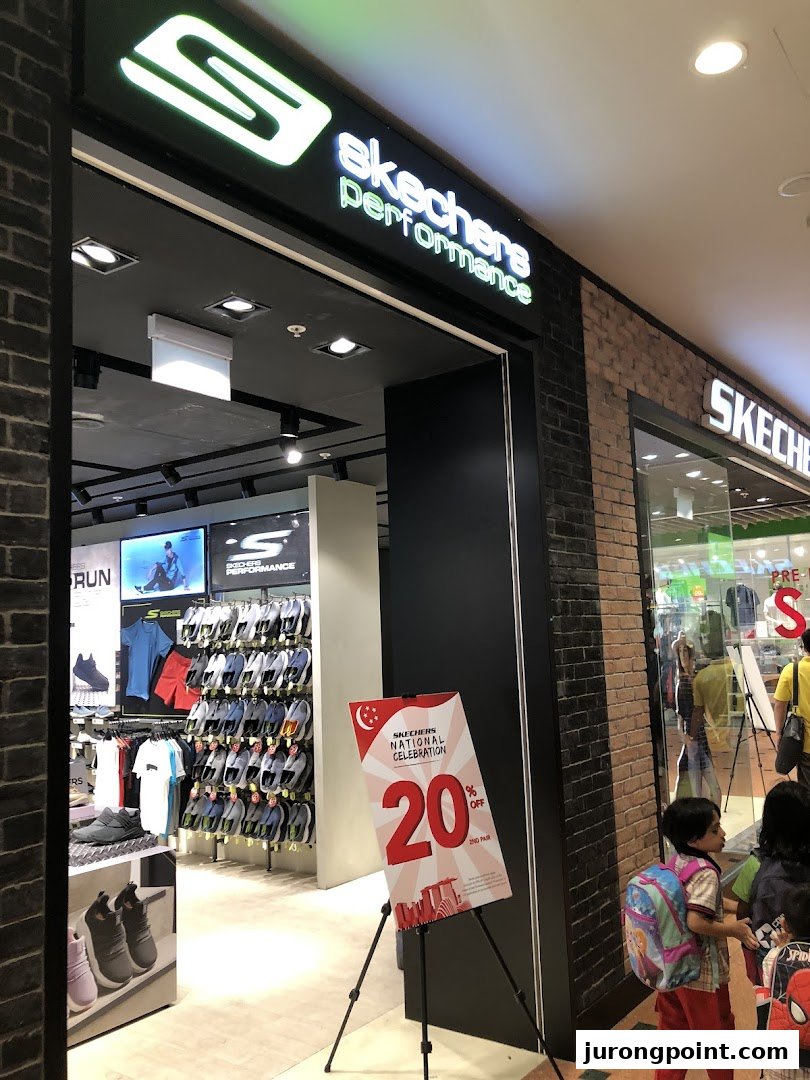 The entrance of a Skechers Performance store showcasing footwear and apparel, with a promotional sign.