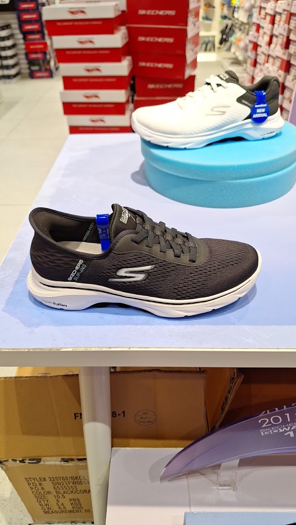 Two Skechers athletic shoes displayed in a retail store, with shoe boxes stacked in the background.