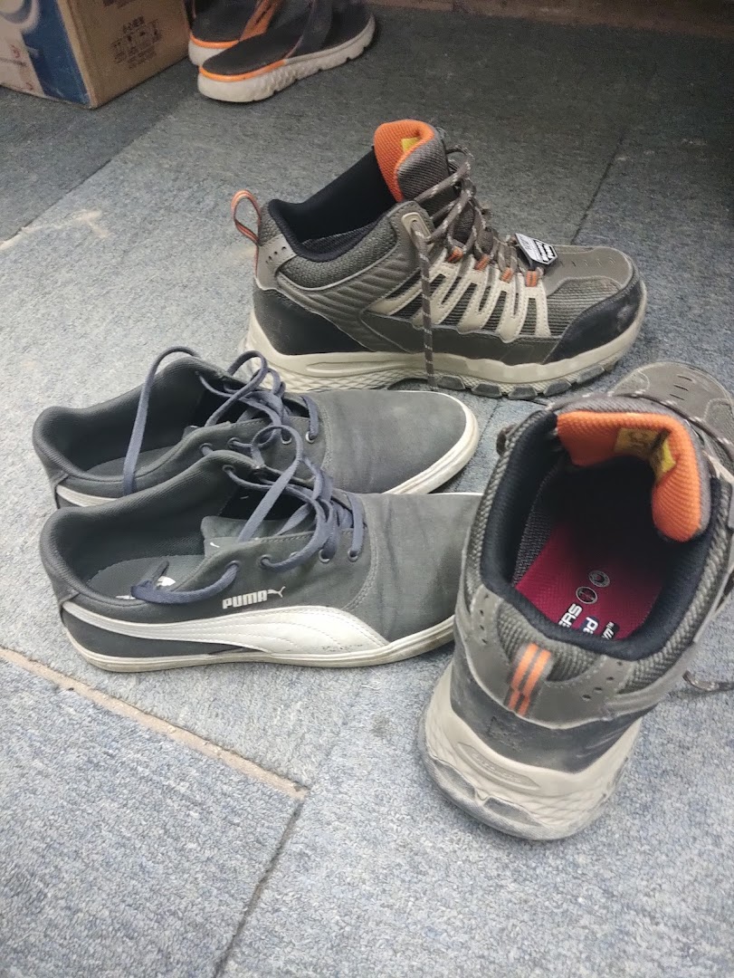 Close-up of various athletic and casual shoes, including Puma and Skechers, on a grey floor.
