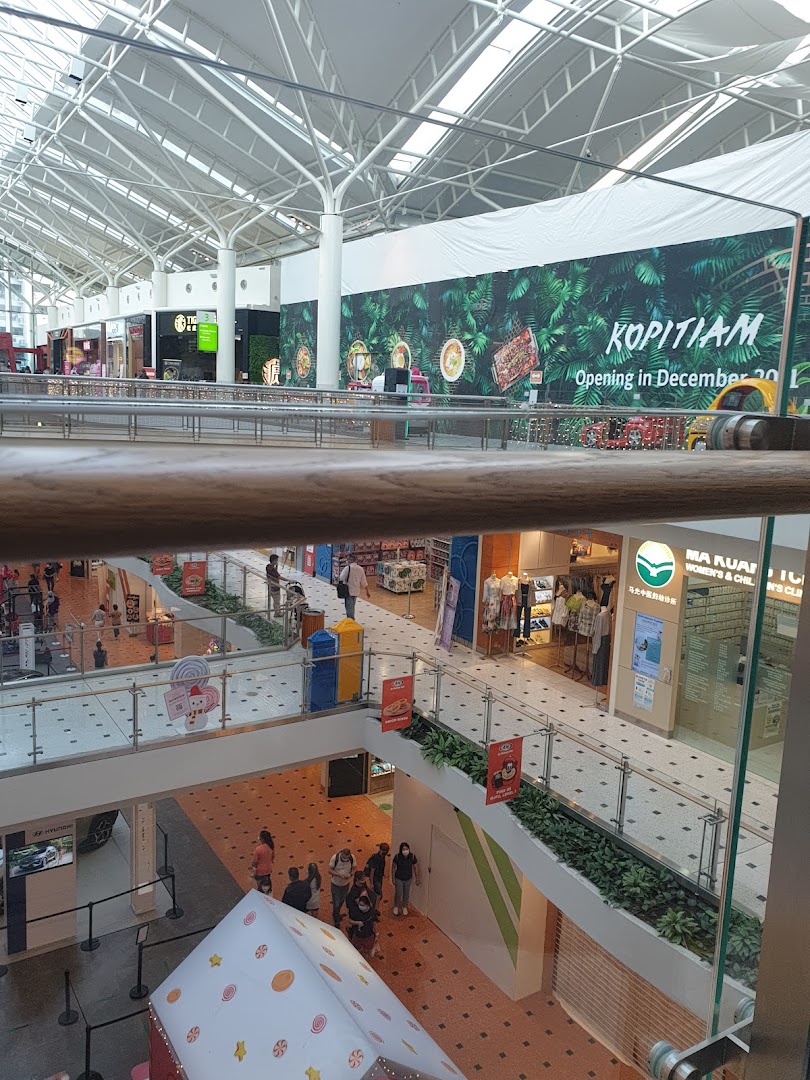 A multi-level mall interior with a high ceiling, showing various shops, a Kopitiam banner, and shoppers.
