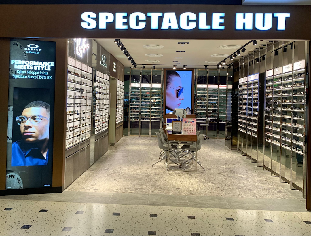 Brightly lit Spectacle Hut entrance showcasing numerous eyewear displays and promotional screens.