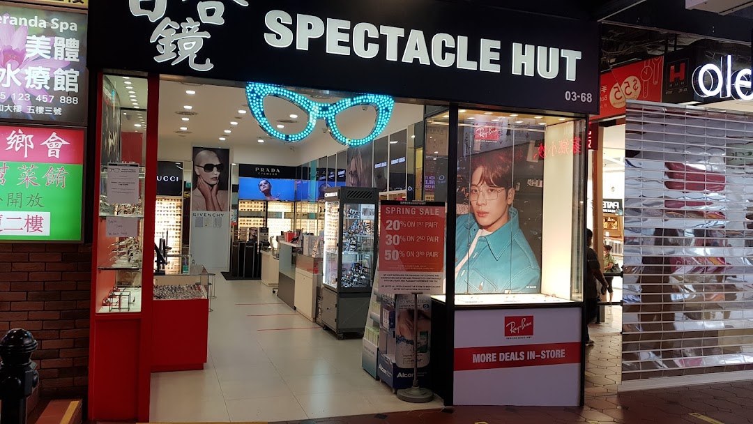 The storefront of Spectacle Hut, featuring a large glasses-shaped neon sign and promotional displays.