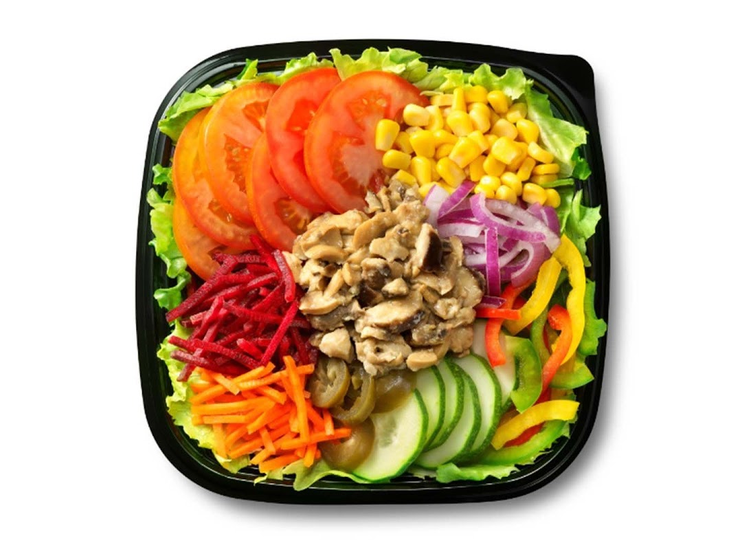 A vibrant, fresh salad in a black bowl, featuring various colorful vegetables and mushrooms.
