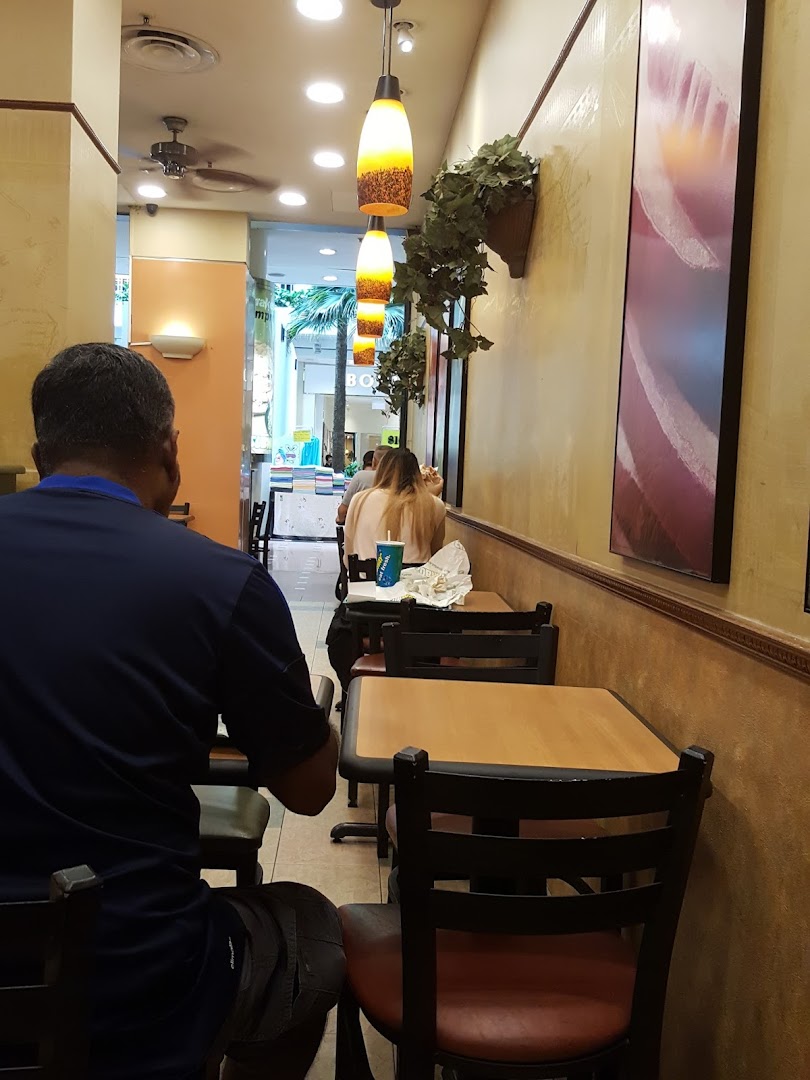 Interior view of a Subway restaurant with customers seated at tables.