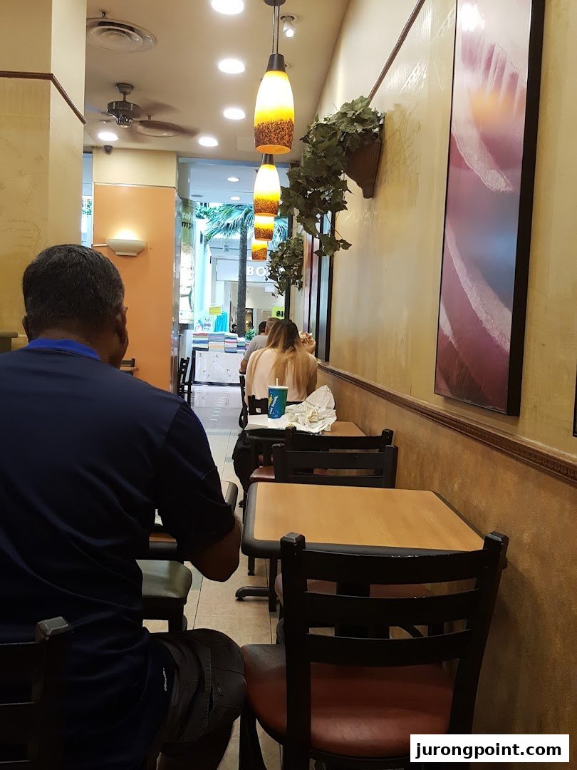 Interior view of a Subway restaurant with customers seated at tables.