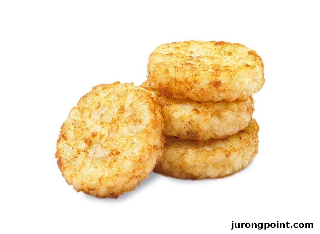 A close-up studio shot of golden-brown hash browns, with one leaning against a stack of three.