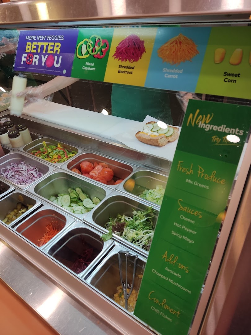 A vibrant Subway counter showcasing fresh vegetables, sauces, and add-ons for custom sandwich creation.