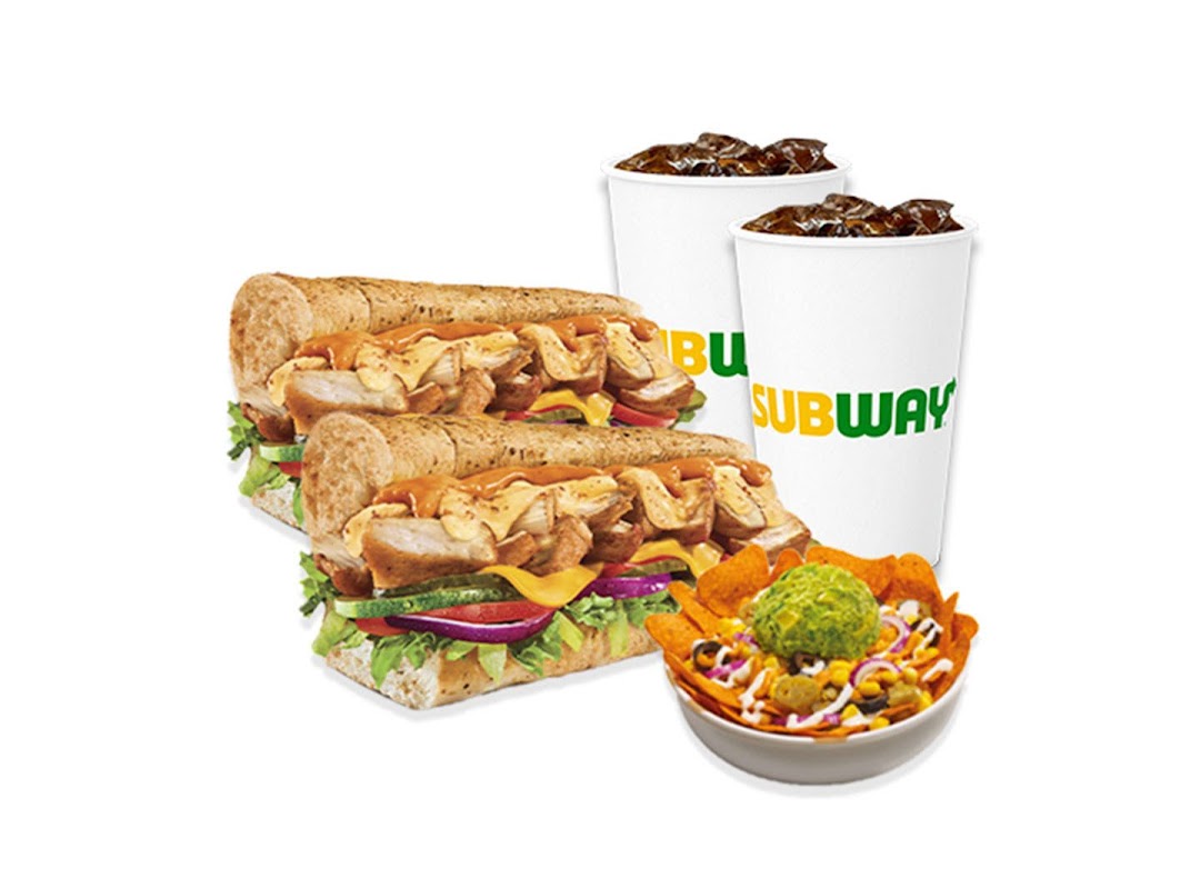 A vibrant image showcasing two Subway subs, two drinks, and a bowl of loaded nachos.
