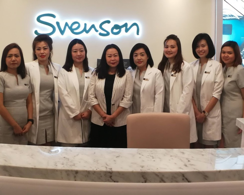 A group of female staff members from Svenson Hair Loss and Scalp Treatment stand together in a modern clinic setting.