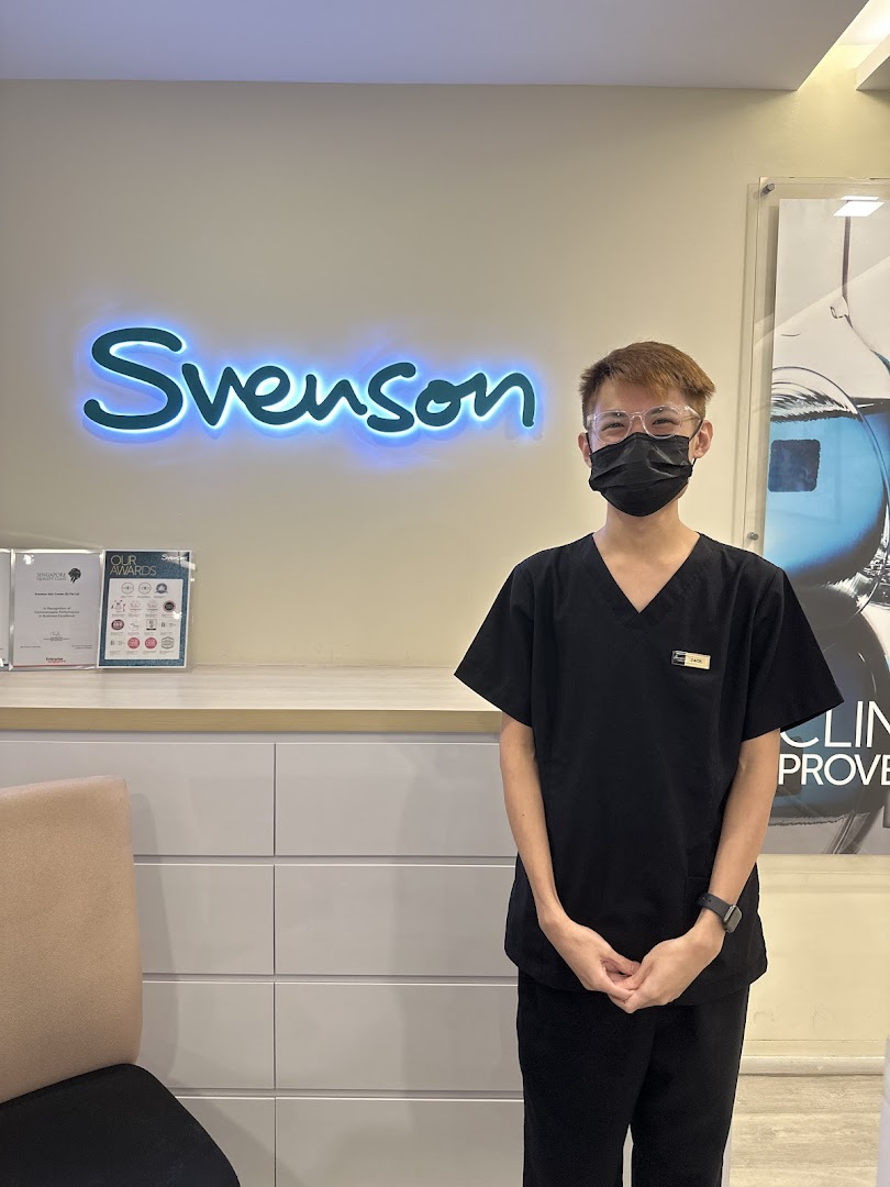 A friendly staff member stands in front of the illuminated Svenson logo, showcasing the clinic's interior.