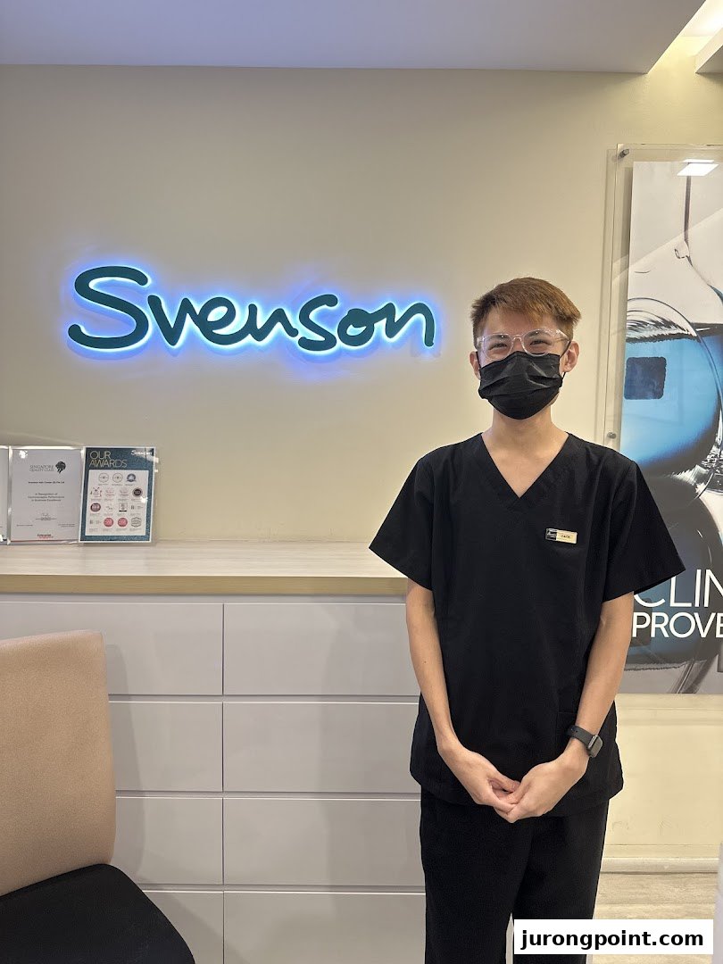A friendly staff member stands in front of the illuminated Svenson logo, showcasing the clinic's interior.