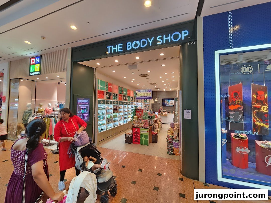 The Body Shop entrance with visible products and shoppers in a bustling mall environment.