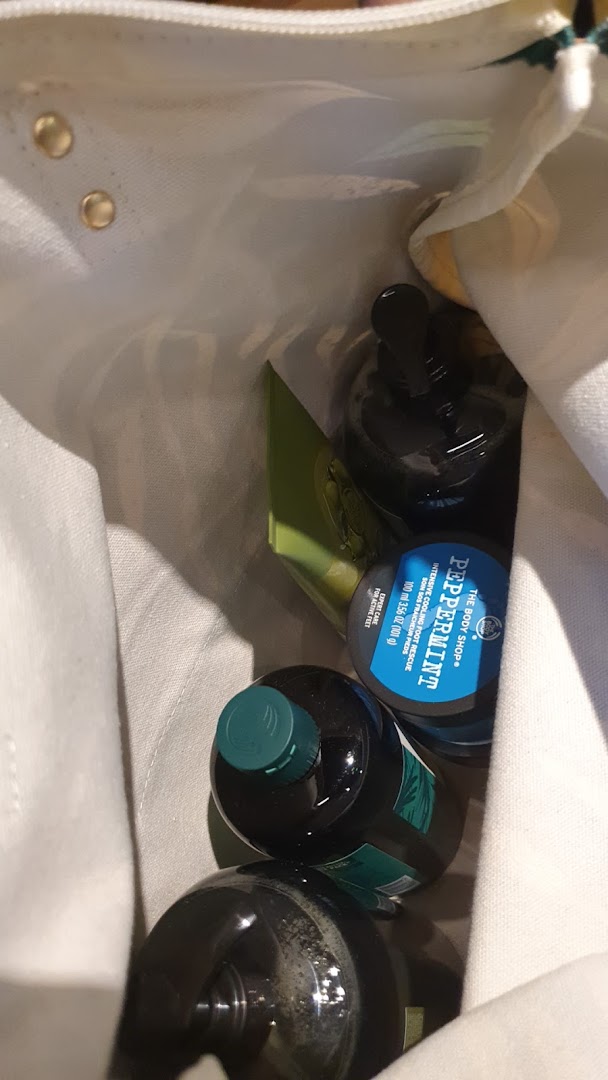 Various The Body Shop products, including Peppermint Intensive Cooling Foot Rescue, inside a white tote bag.