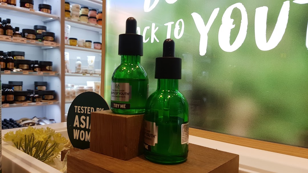 Two green bottles of The Body Shop's 'Drops of Youth' concentrate on display, with other products in the background.