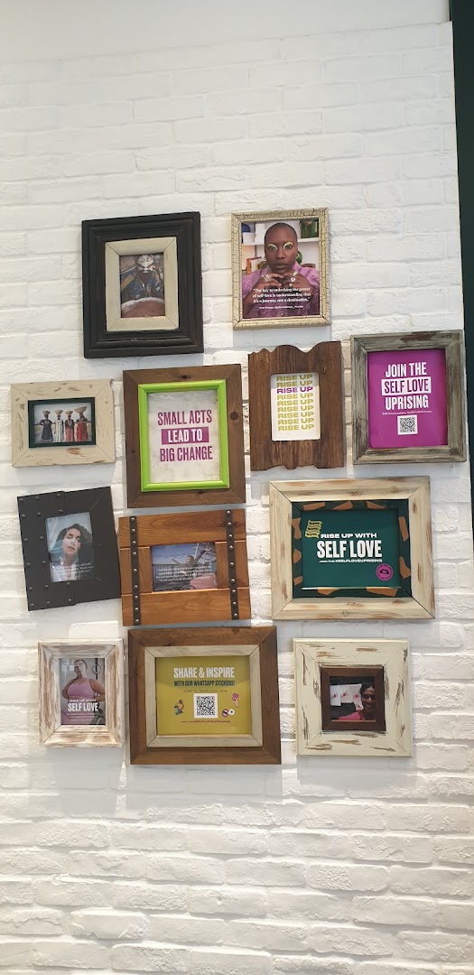 A white brick wall adorned with framed pictures and motivational messages promoting self-love and positive change.