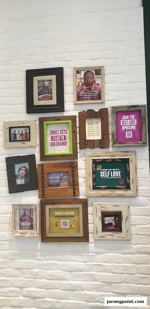 A white brick wall adorned with framed pictures and motivational messages promoting self-love and positive change.