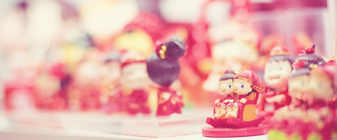 Close-up of charming Chinese wedding figurines, including a couple on a rocking chair, displayed in a shop.