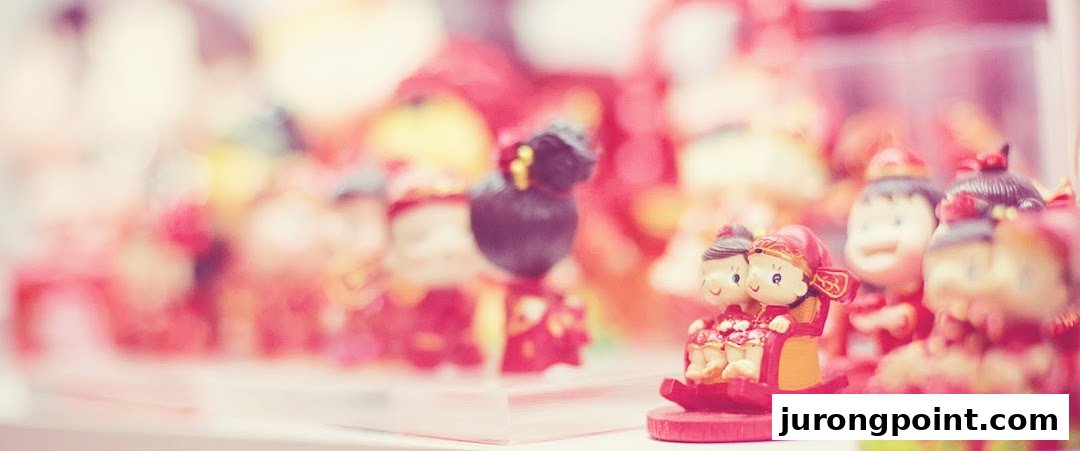 Close-up of charming Chinese wedding figurines, including a couple on a rocking chair, displayed in a shop.