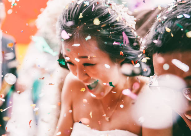 A joyful bride smiles amidst colorful confetti, celebrating a special wedding moment.