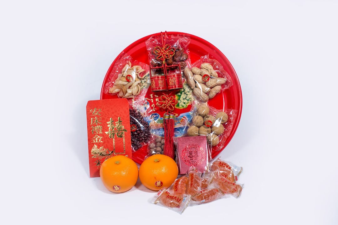 A red tray filled with traditional Chinese wedding items, including nuts, dried fruits, and red packets.