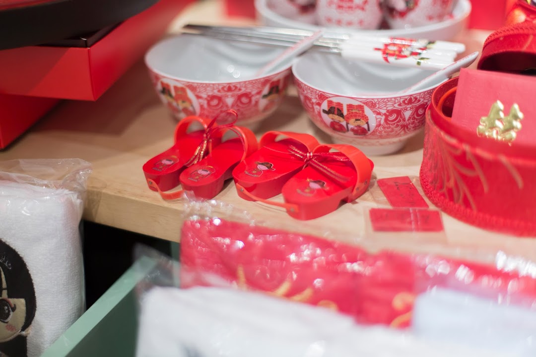 Close-up of traditional red Chinese wedding items, including bowls, chopsticks, and decorative shoes.