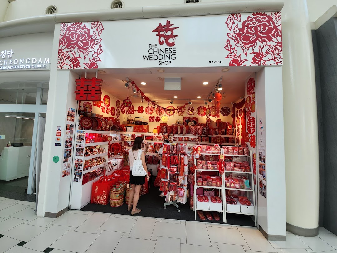 The shop front of 'The Chinese Wedding Shop' displaying traditional red wedding items, with a customer browsing inside.