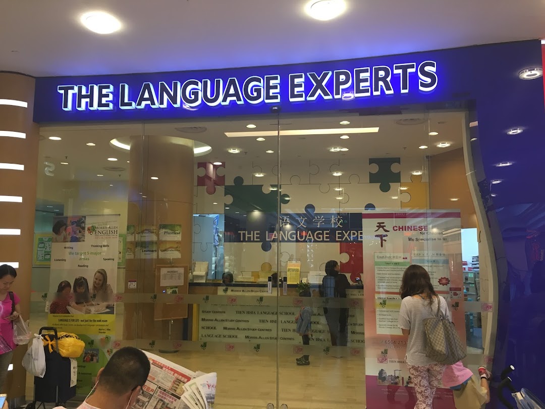 The brightly lit entrance of Tien Hsia Language School, featuring its prominent 'The Language Experts' sign.