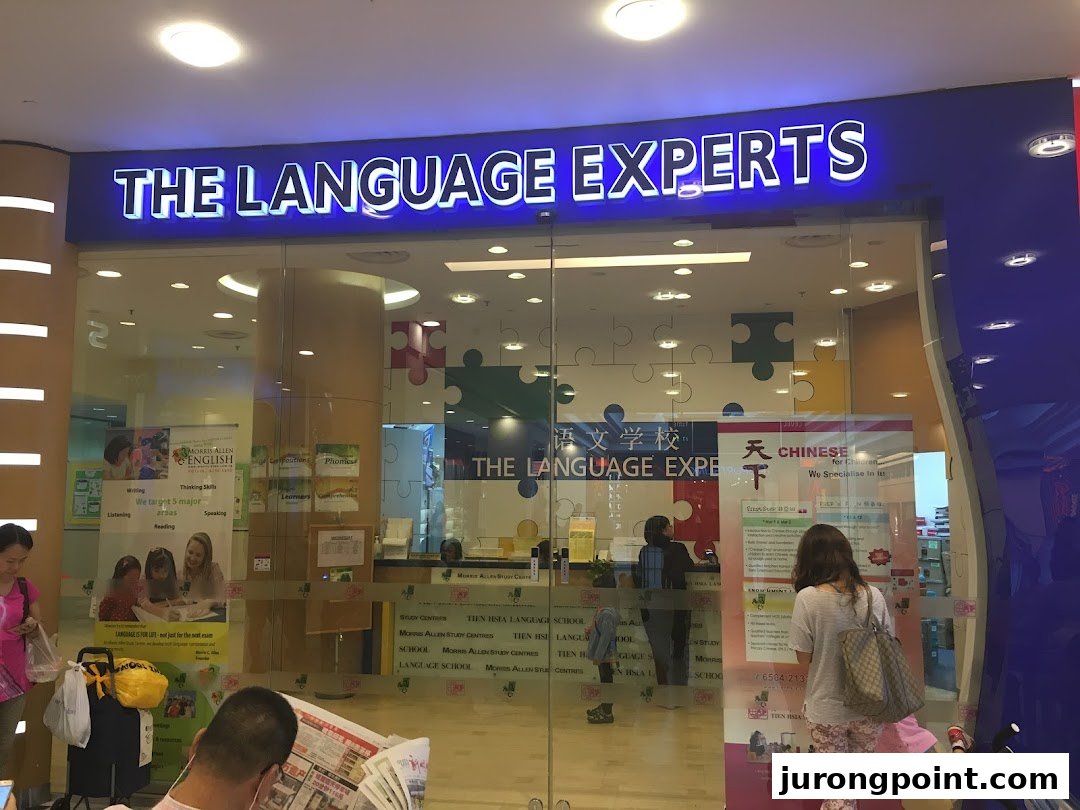 The brightly lit entrance of Tien Hsia Language School, featuring its prominent 'The Language Experts' sign.