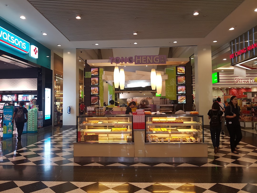 A bright Tong Heng pastry kiosk in a bustling shopping mall, showcasing a variety of traditional baked goods.