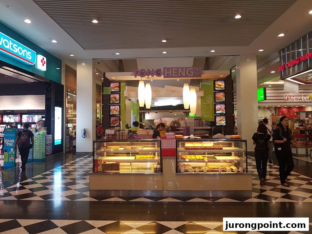 A bright Tong Heng pastry kiosk in a bustling shopping mall, showcasing a variety of traditional baked goods.