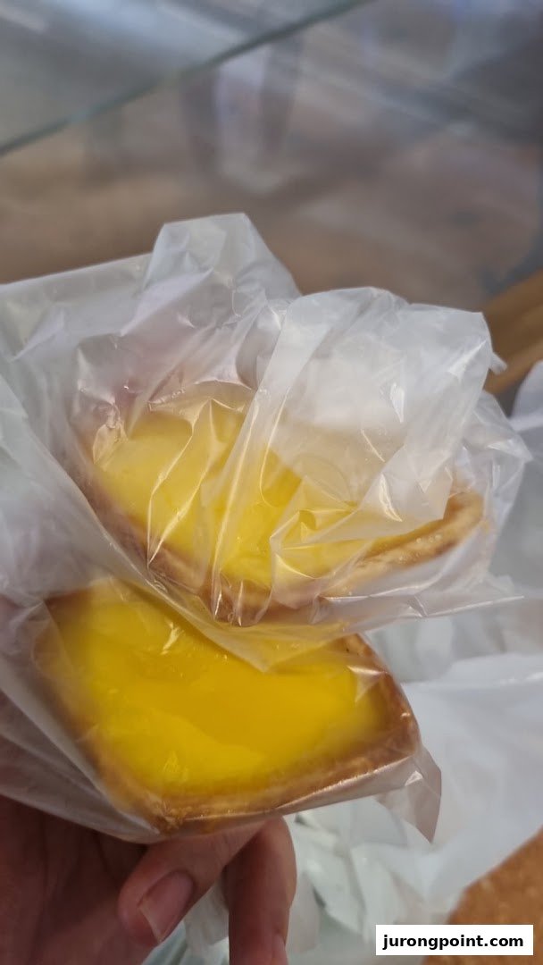 Two delicious Tong Heng egg tarts, individually wrapped and ready to enjoy.