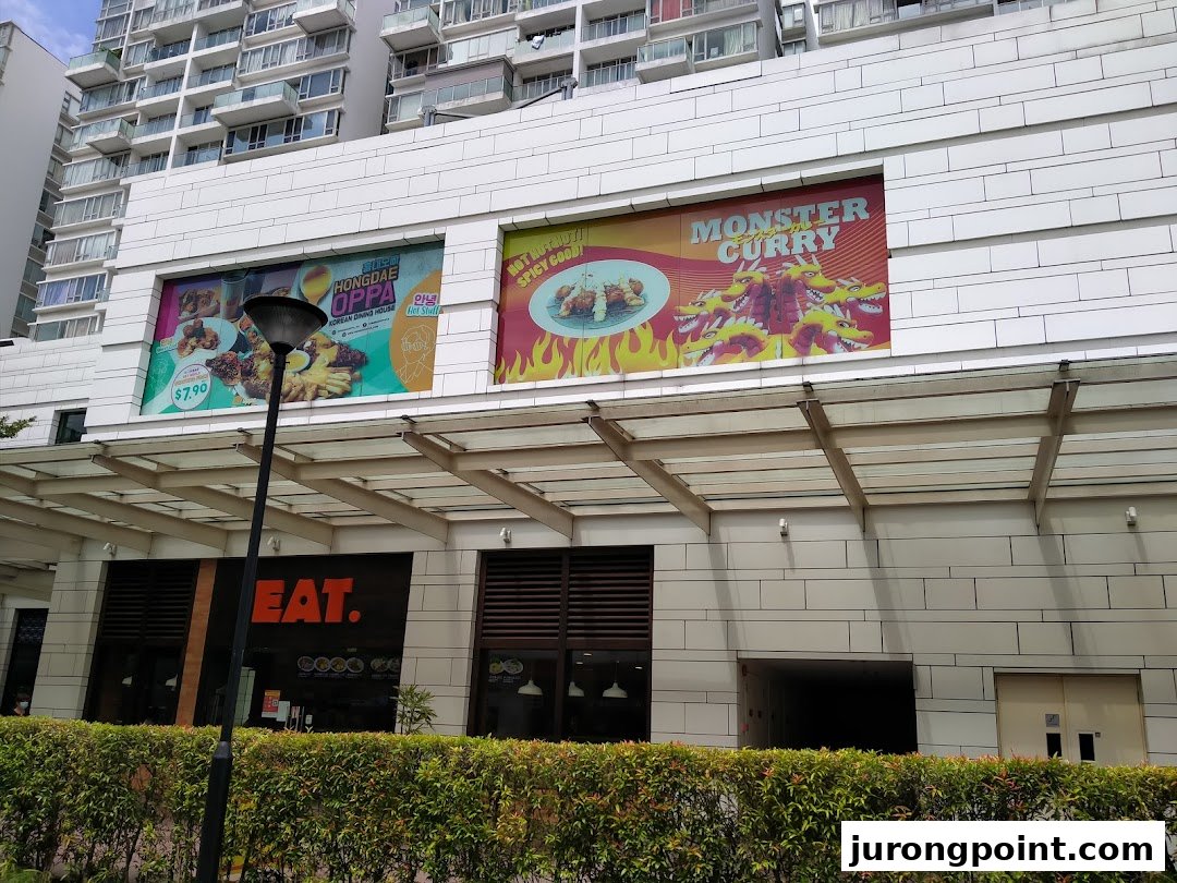Exterior view of a building featuring large food advertisements for Hongdae Oppa and Monster Curry, with an 'EAT.' shop entrance.