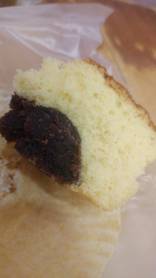 A close-up of a slice of fluffy sponge cake with a rich red bean paste filling.