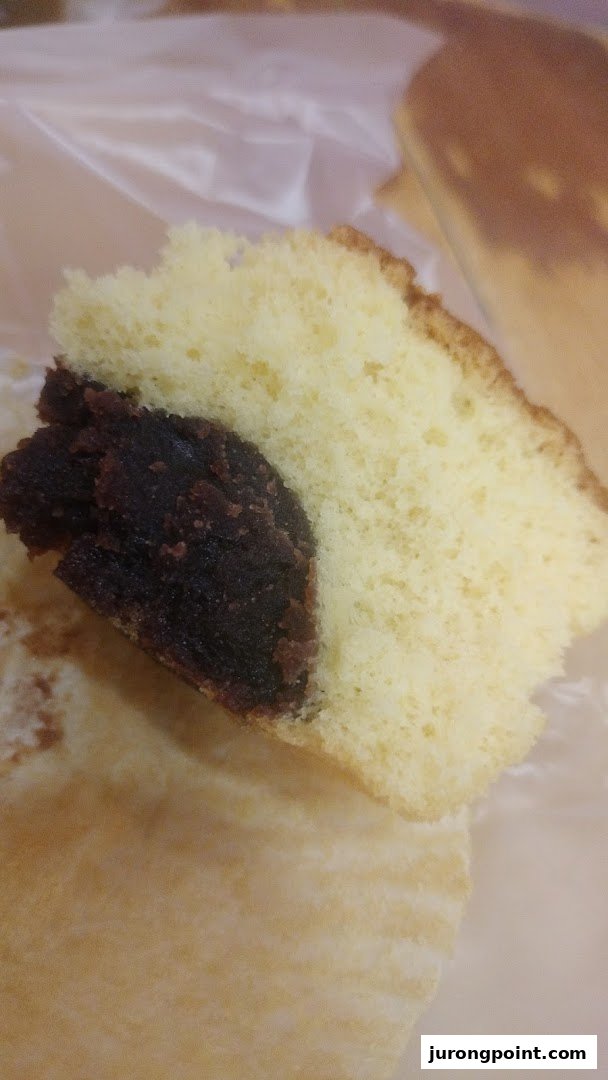 A close-up of a slice of fluffy sponge cake with a rich red bean paste filling.