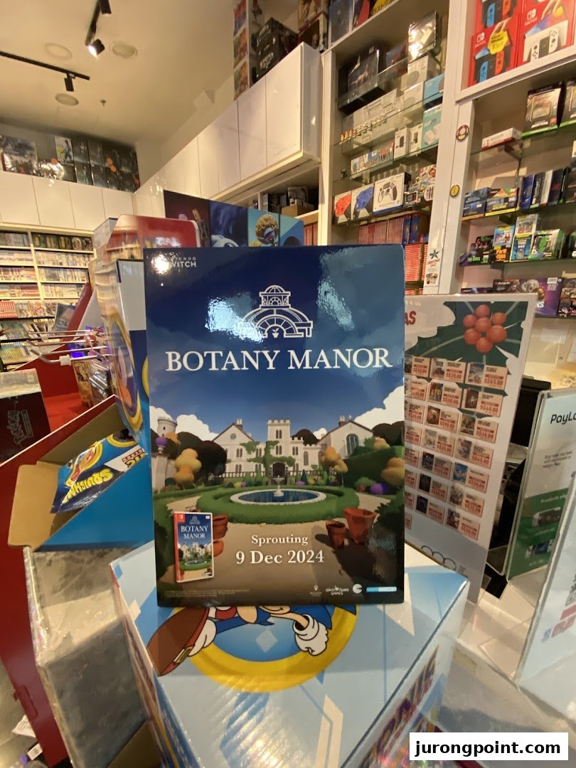 An in-store display featuring 'Botany Manor' game, surrounded by shelves of video games and consoles.
