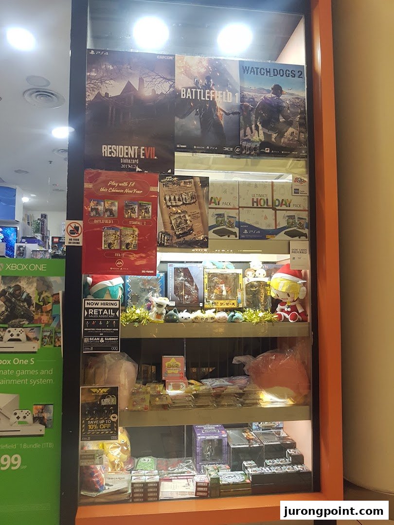 A brightly lit display case showcasing video game posters, console bundles, and various gaming merchandise.