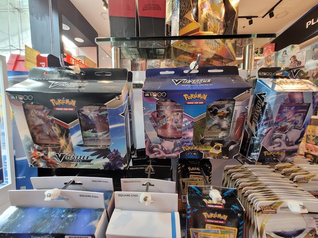 Close-up view of various Pokémon Trading Card Game products and other merchandise displayed in a toy and game shop.