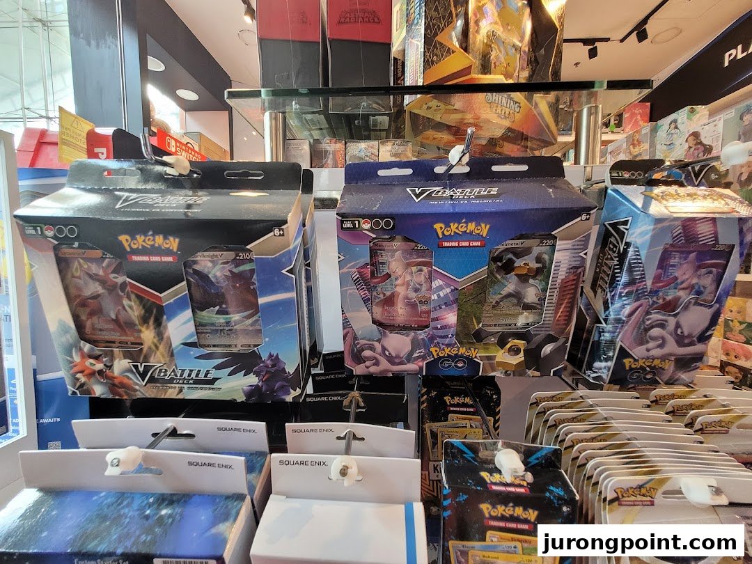 Close-up view of various Pokémon Trading Card Game products and other merchandise displayed in a toy and game shop.