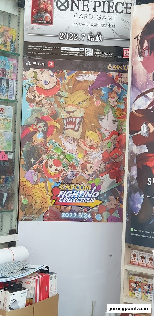 Promotional posters for One Piece Card Game and Capcom Fighting Collection displayed inside a game store.