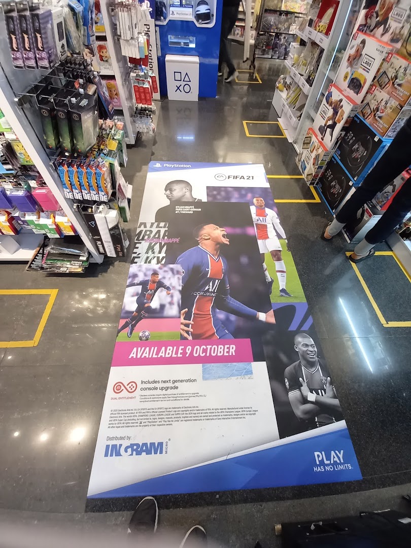 Interior view of a Toy Or Game TOG store featuring a large FIFA 21 floor advertisement and product shelves.