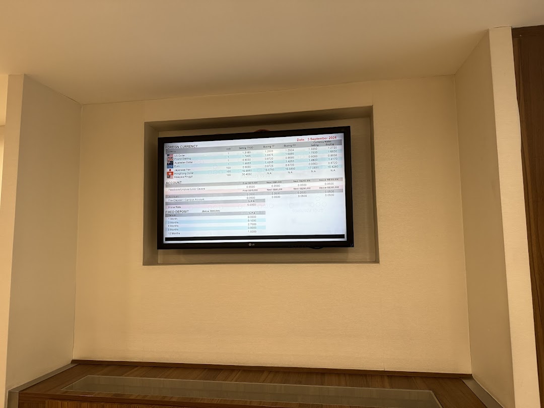 A digital display inside a bank branch showing foreign currency exchange rates and account information.