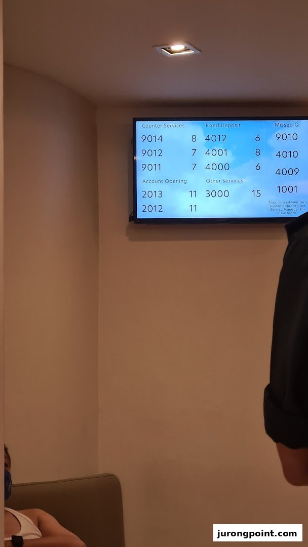 A digital queue management screen displaying service numbers at a bank branch.
