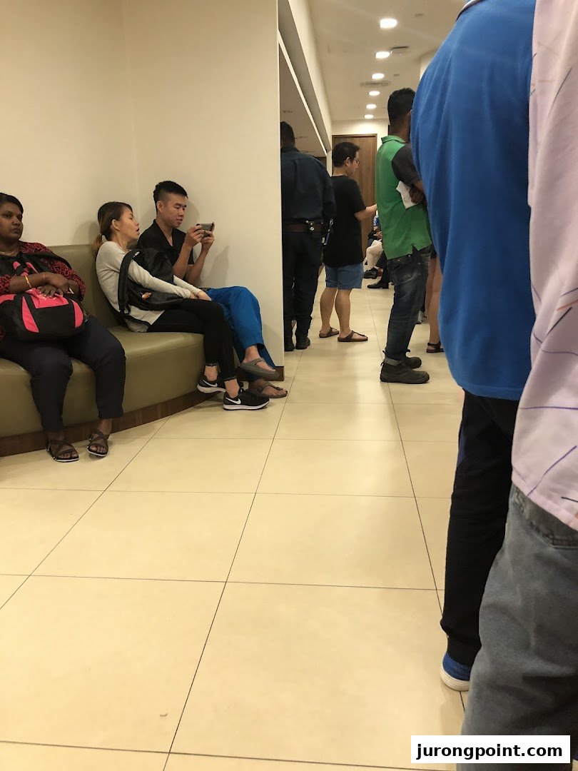 Customers waiting in a UOB bank branch, some seated, others standing in line.