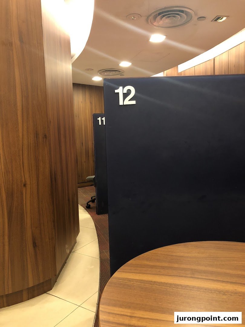 Interior view of UOB bank branch with numbered private booths and modern wooden paneling.