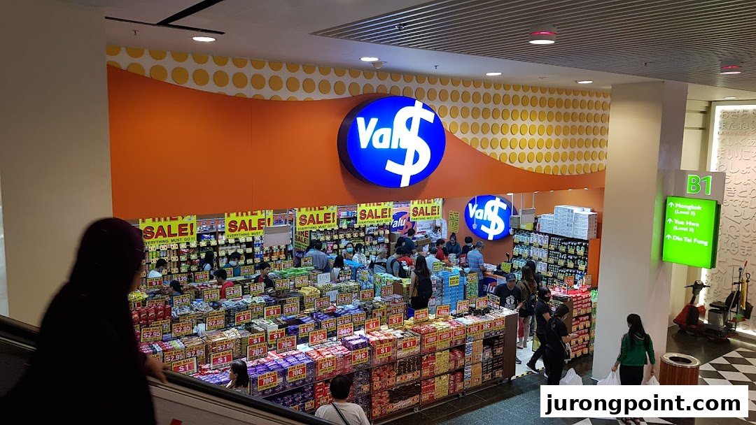 The vibrant orange entrance of Valu discount store, showcasing numerous products and customers inside.