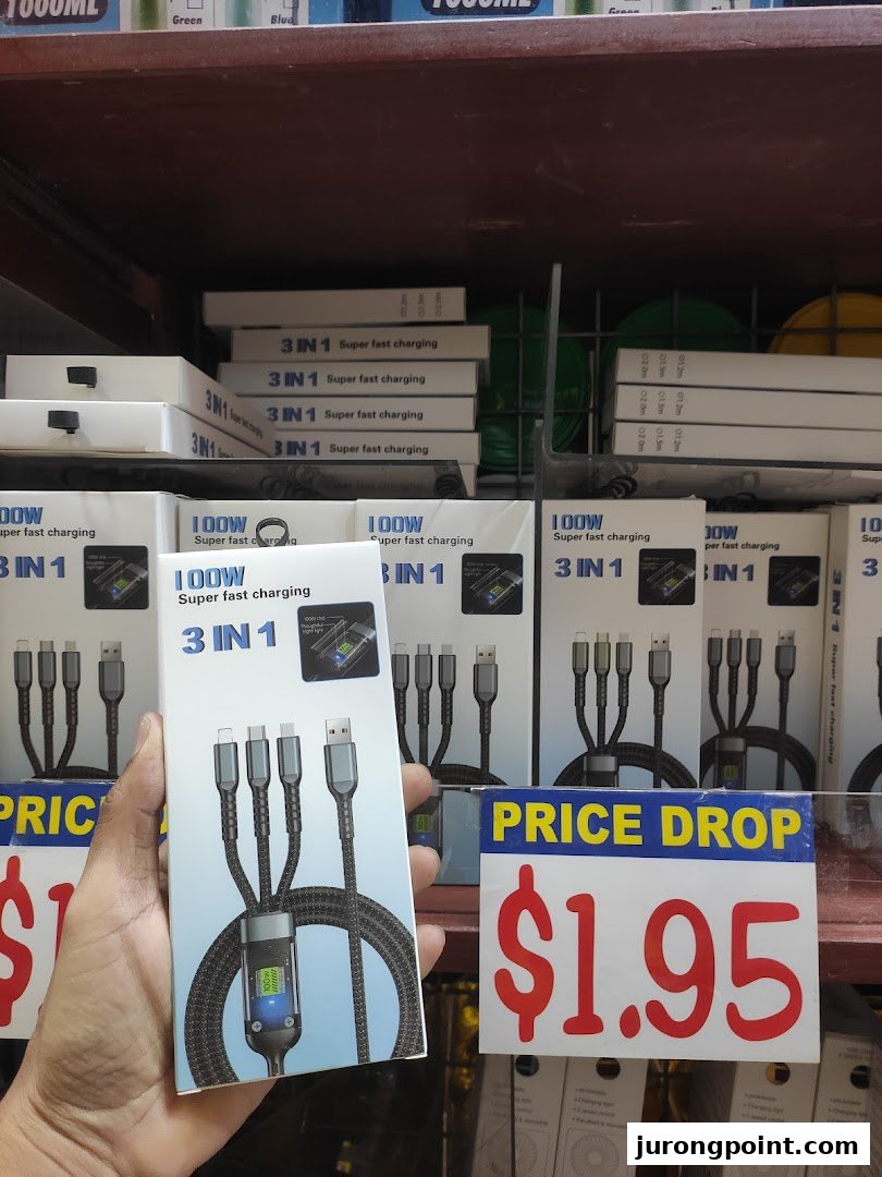 A hand holds a 3-in-1 super fast charging cable box, with more products and a '$1.95 PRICE DROP' sign on shelves.