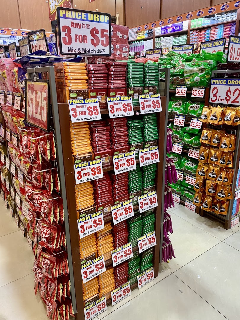 Aisle view of Valu supermarket featuring shelves stocked with snacks, chocolates, and 'Price Drop' deals.