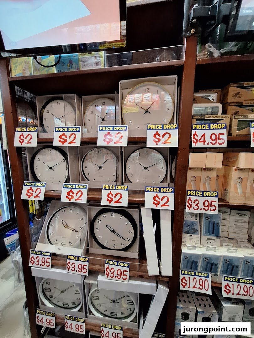 A retail display shelf at Valu showcasing various clocks and electronics with prominent 'Price Drop' signs.